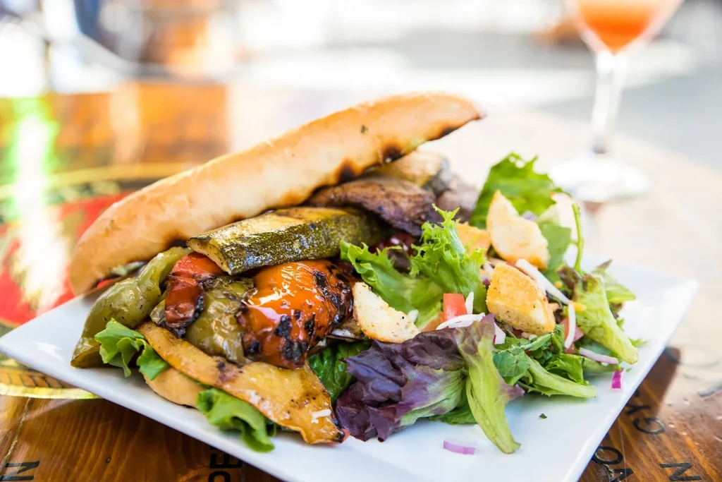 Plate of grilled zucchini, bell peppers, baguette, and green salad.