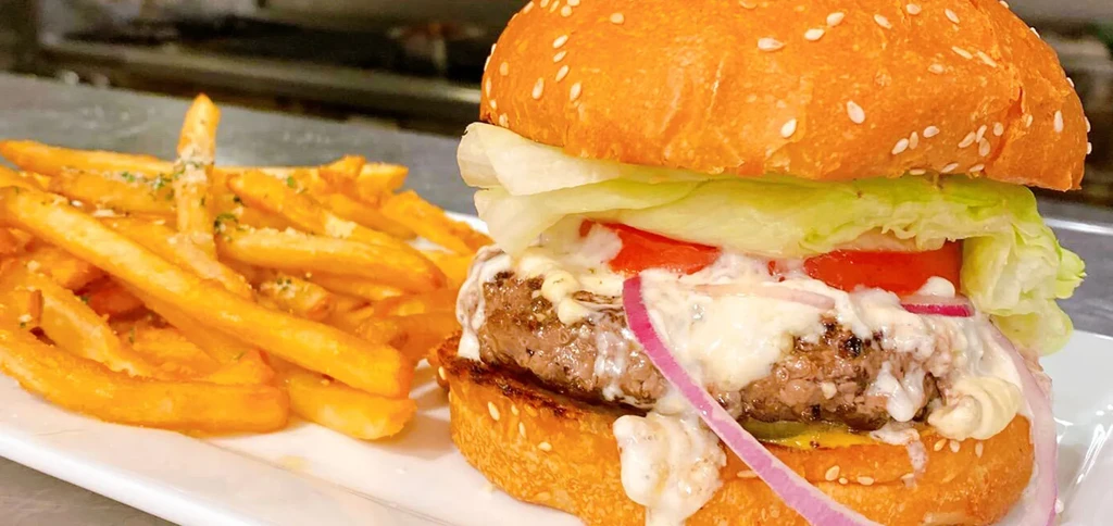 Gourmet beef burger with cheese, tomato, lettuce, and herb-dusted fries.