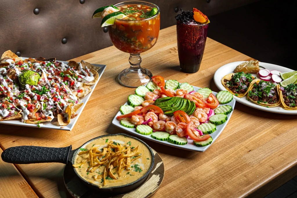 Mexican food spread: nachos, tacos, queso, shrimp, and cocktails.