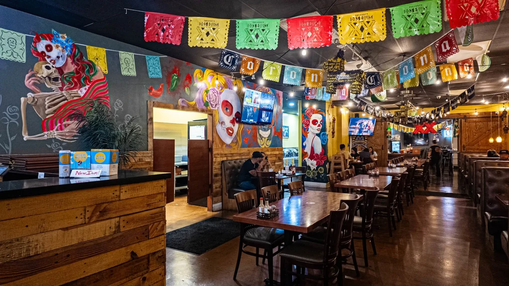Colorful Mexican restaurant interior with Day of the Dead murals and festive decor.