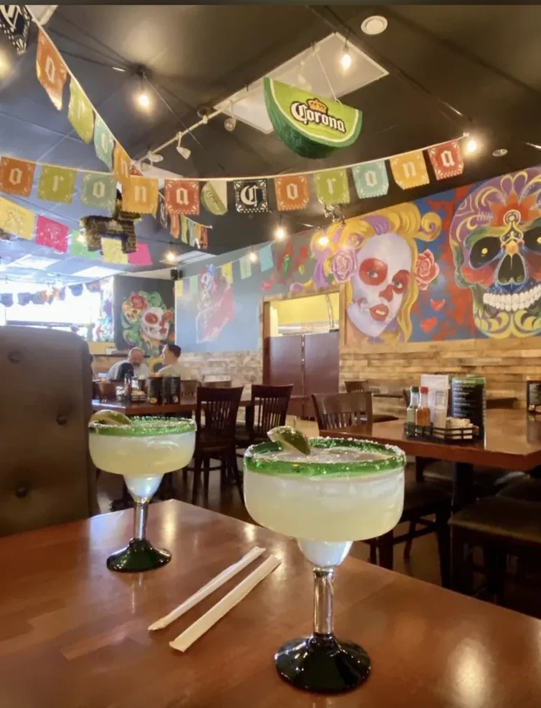 Two large margaritas in a colorful Day of the Dead restaurant.