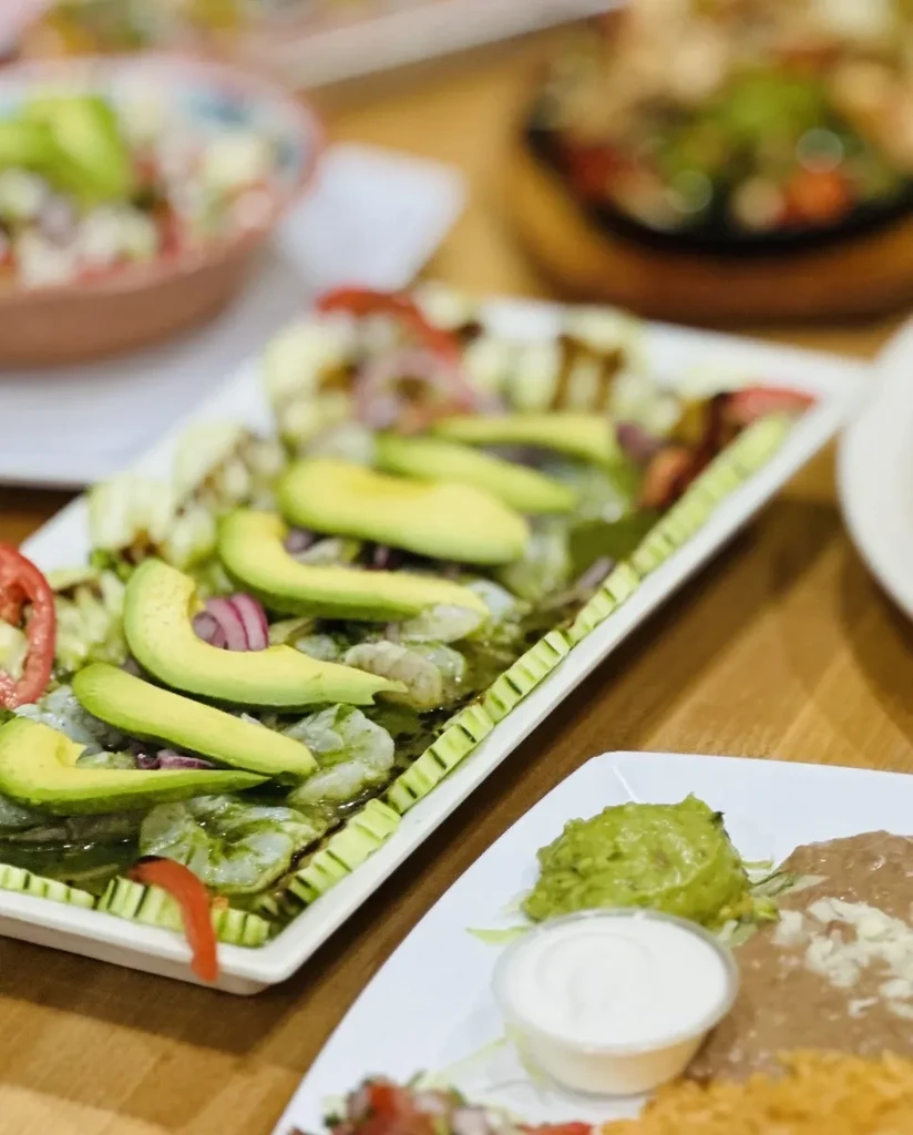 Close-up of seafood ceviche with avocado, guacamole, and refried beans.