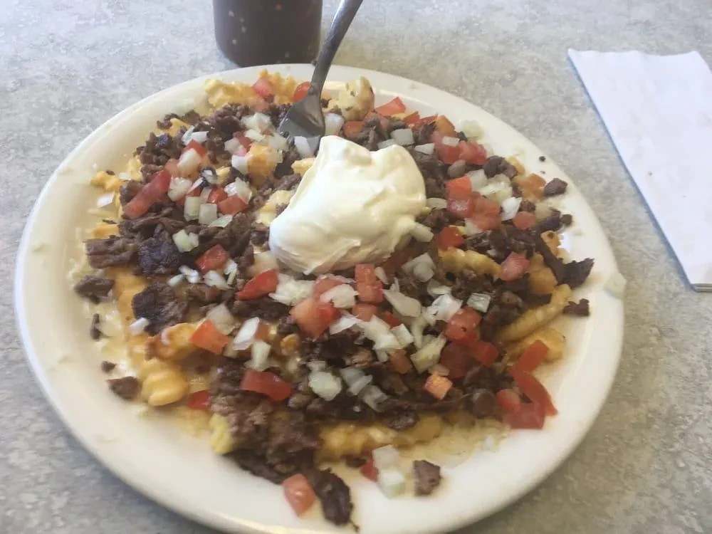Loaded waffle fries with steak, tomatoes, onions, and white sauce.