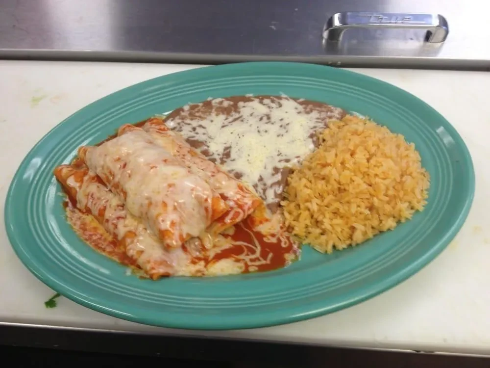 Close-up of Mexican enchiladas, rice, and beans on a turquoise plate.