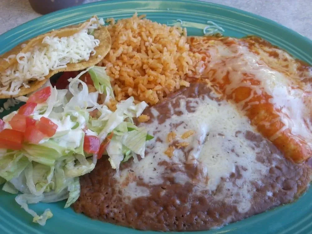 Teal plate with Mexican combination: tacos, enchiladas, rice, and refried beans.