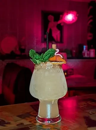Mushroom-shaped glass cocktail with mint, citrus, and a swan pick in dramatic lighting.