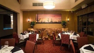 Upscale Southwestern dining room, set tables, saguaro cactus painting on wall.