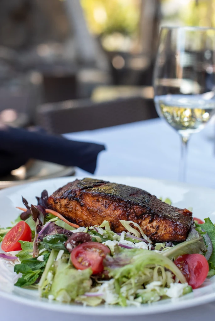 Seared salmon and mixed green salad with cheese, outdoors.