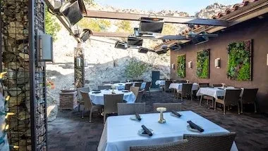 Elegant outdoor dining patio with gabion wall and vertical gardens.