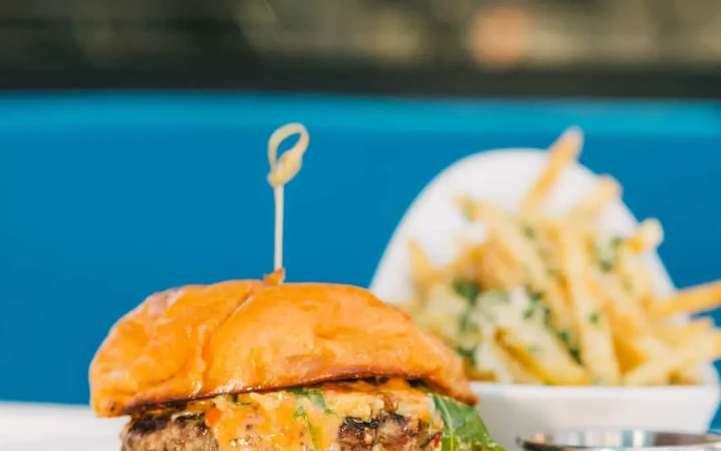 Gourmet burger with sauce, lettuce, skewer, and seasoned fries.