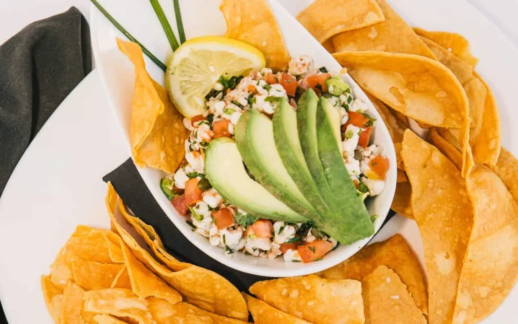 Seafood ceviche garnished with avocado, lemon, and tortilla chips.