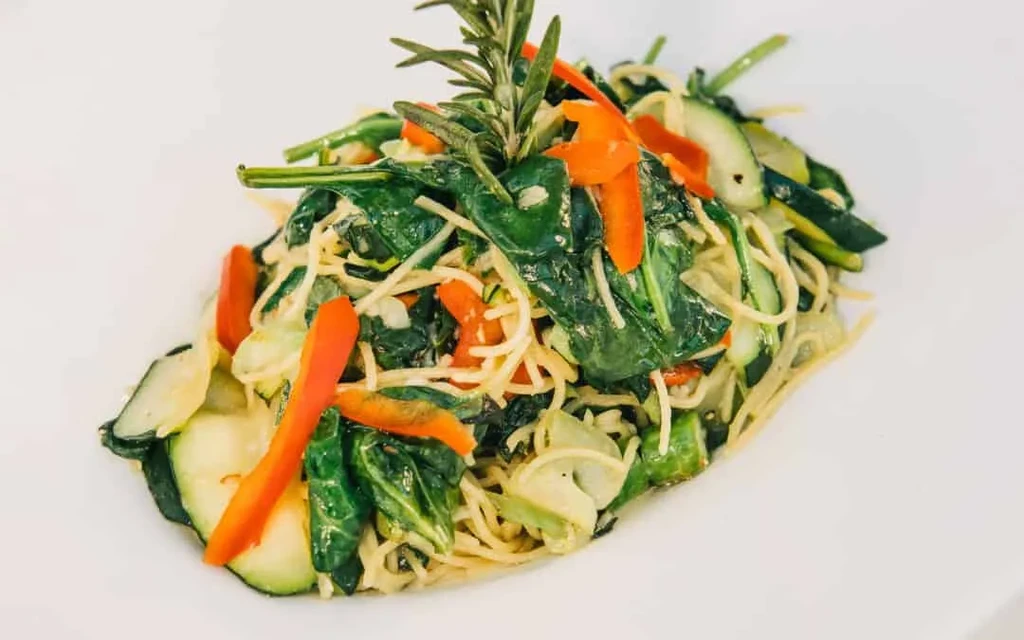 Colorful vegetarian pasta with spinach, zucchini, bell pepper, and rosemary.
