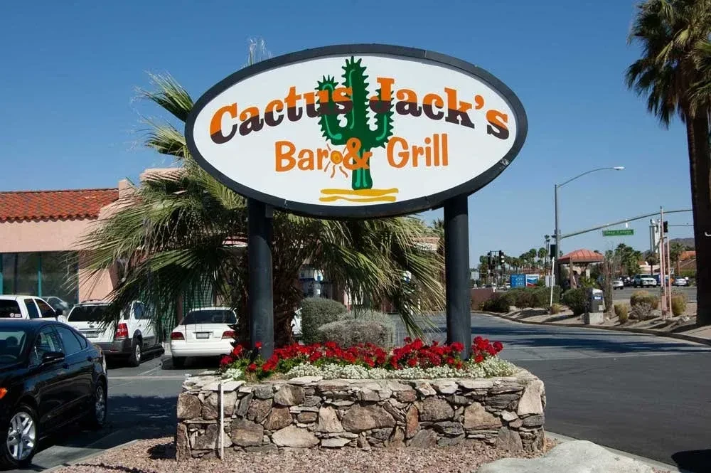 Cactus Jack's Bar & Grill sign with cactus, flowers, and palm trees.