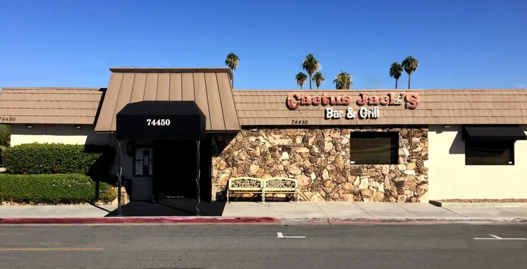 Cactus Jack's Bar & Grill exterior with stone, cream walls, and palm trees.