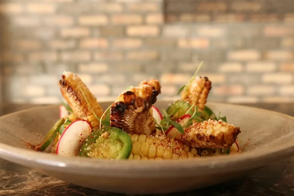Grilled corn on the cob and kernels, garnished with radish, jalapeño.