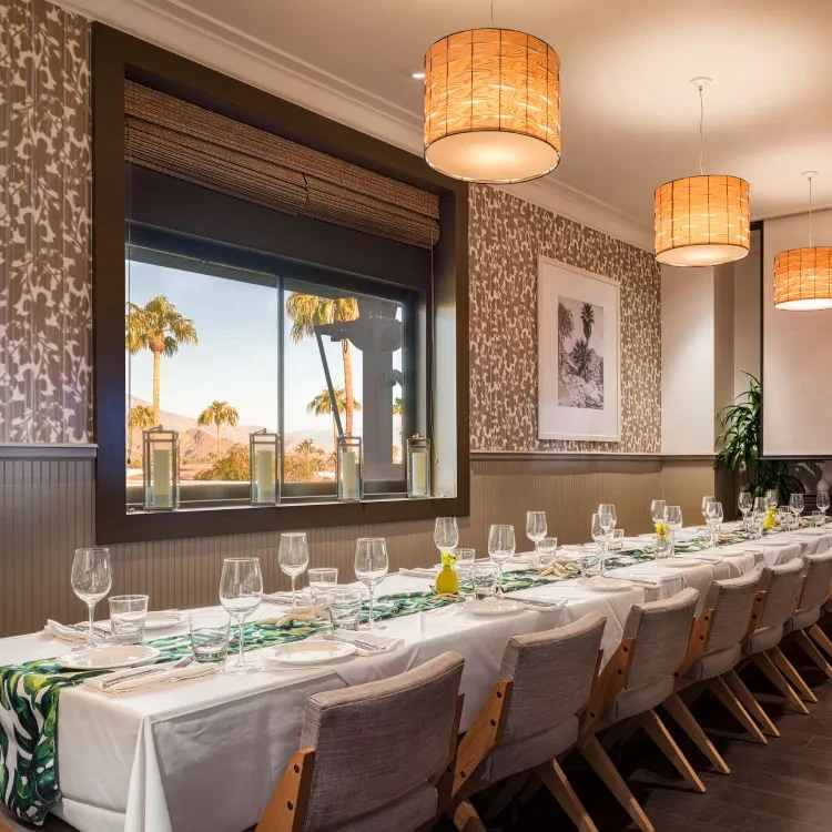 Long dining table with tropical runner overlooks desert landscape.