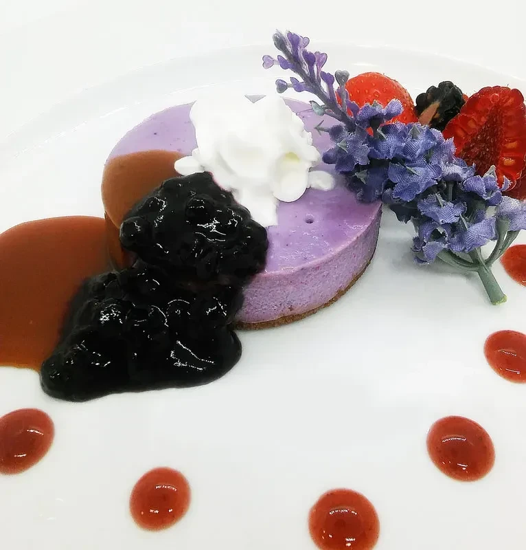 Purple tart, whipped cream, blueberry compote, berries, lavender, and sauces.
