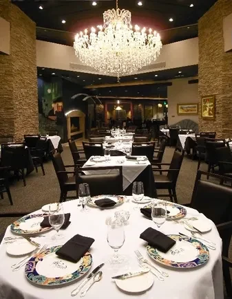 Empty elegant restaurant dining area with set tables and crystal chandelier.