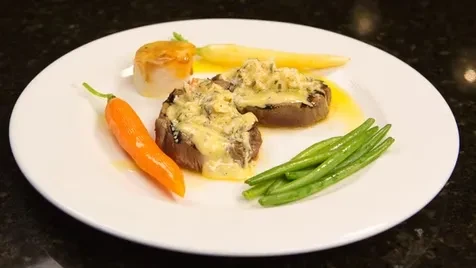 Two seared meat medallions with creamy sauce, green beans, and vegetables.