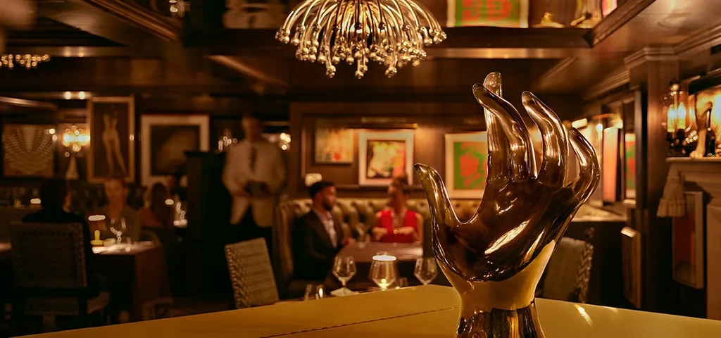 Elegant, dimly lit restaurant interior featuring a golden hand sculpture.
