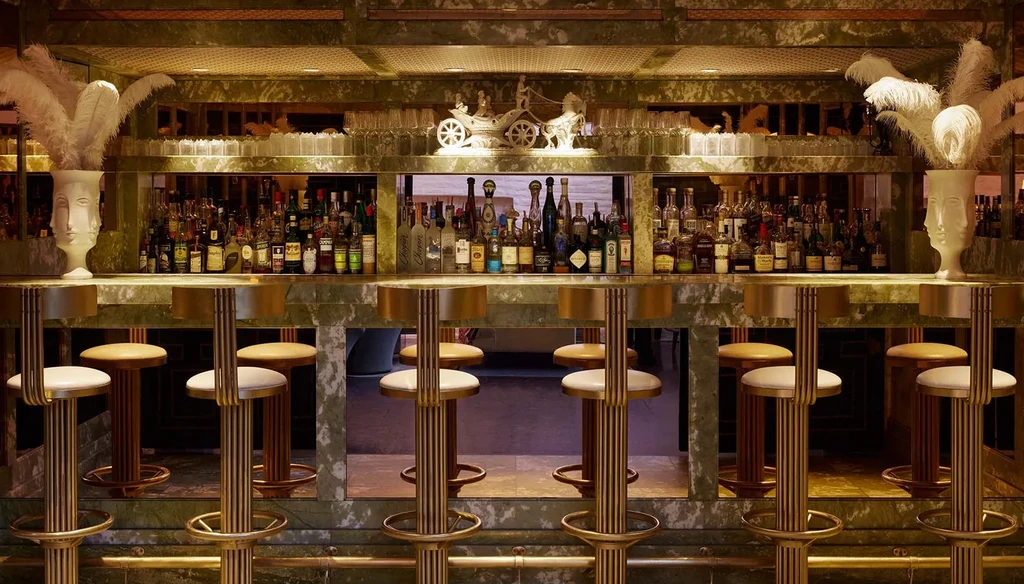 Elegant green marble bar, stocked liquor shelves, feather vases, chariot sculpture.