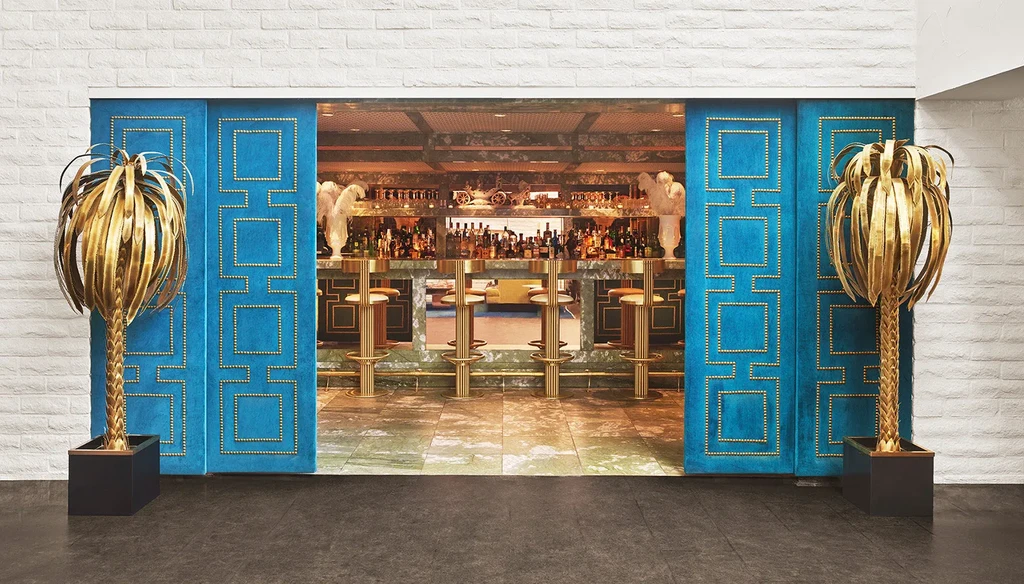 Blue velvet doors, golden palms, and green marble bar interior.