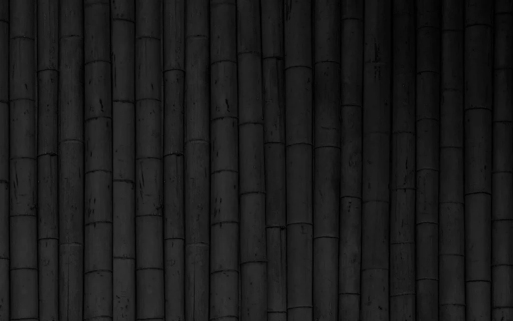 Dark, textured wall of charcoal gray bamboo poles.