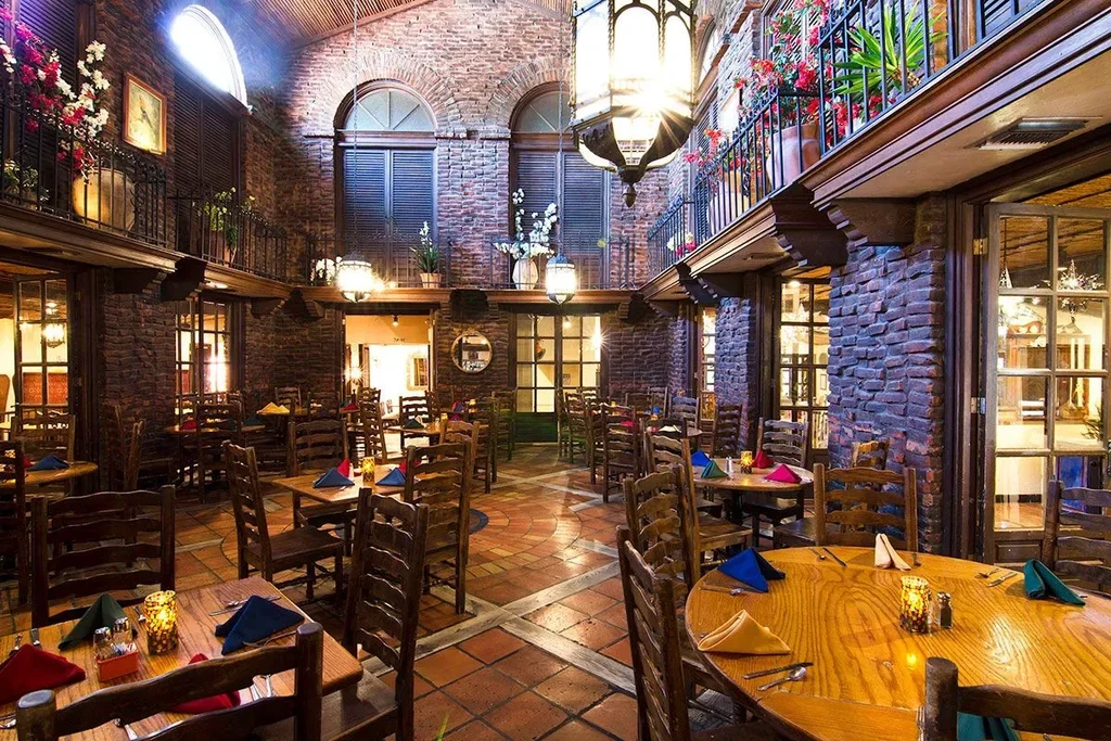 Rustic restaurant interior with brick, wood, and set tables.