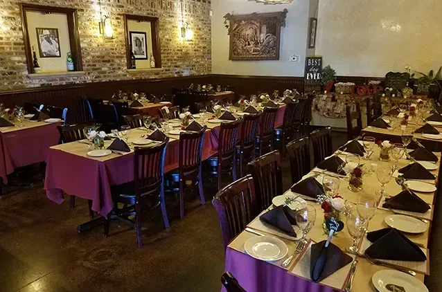 Warmly lit restaurant dining room with tables set for a special event.