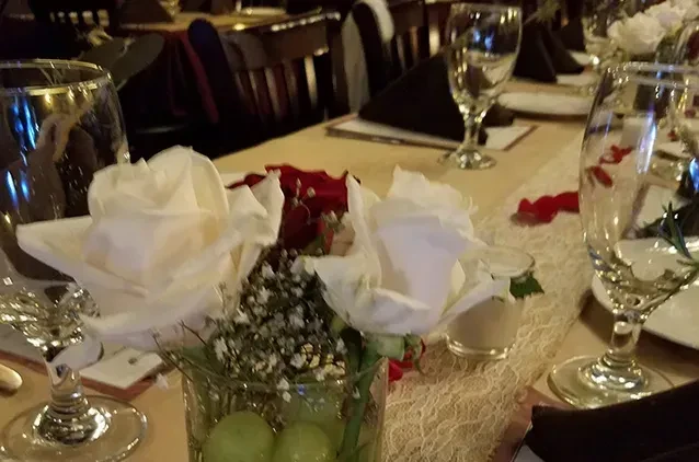 Decorated restaurant table with a floral centerpiece of white and red roses.