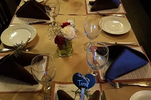 Set dining table with rose centerpiece, votive candle, and 'Terry' place card.
