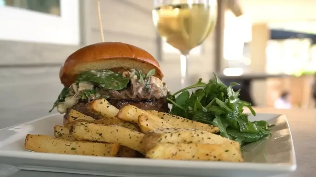 Plated gourmet burger, thick-cut fries, and fresh green salad.