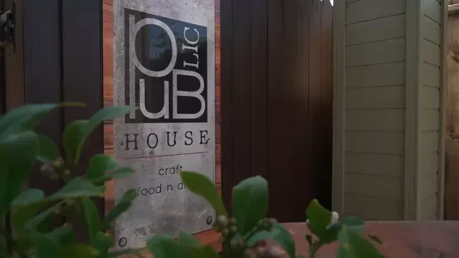 Vertical 'PUBLIC HOUSE' sign, 'craft food n art,' on dark wood.