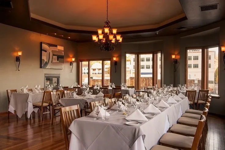 Elegant restaurant dining room with formal table settings and warm lighting.
