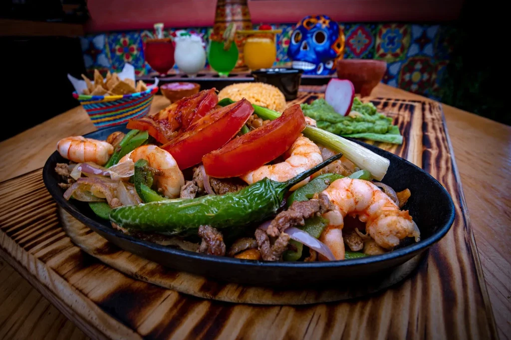 Sizzling beef and shrimp fajitas in a black cast iron skillet.
