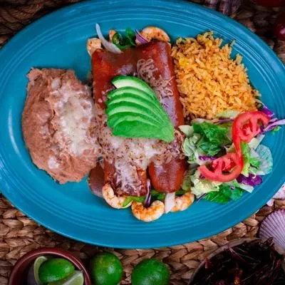 Overhead Mexican meal: enchiladas, beans, rice, and salad on a teal plate.