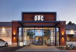 Modern commercial building exterior at dusk with illuminated "OBC" sign.