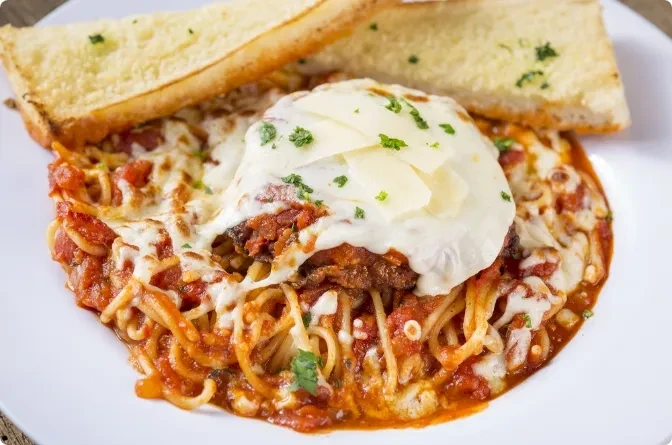 Spaghetti with breaded cutlet, marinara, mozzarella, parmesan, and garlic bread.