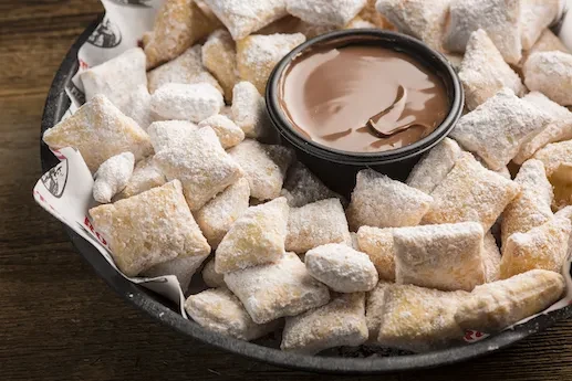 Small, powdered sugar-dusted pastries with chocolate dipping sauce.