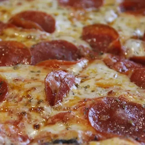 Close-up of freshly baked pepperoni pizza with melted cheese and herbs.
