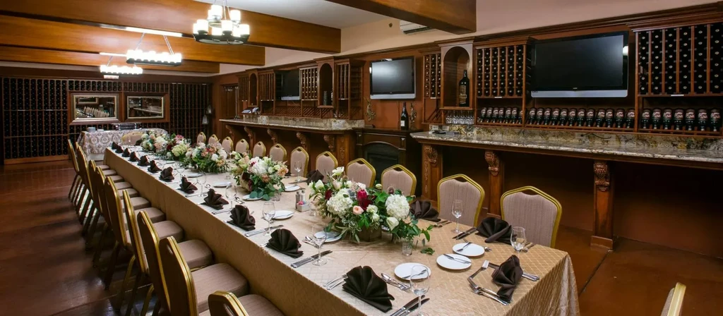 Luxurious private dining room with long, elegant table and floral centerpieces.