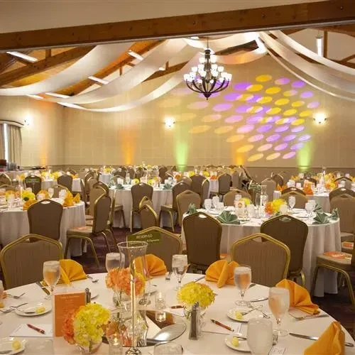 Formal banquet hall with round tables, floral centerpieces, and decorative lighting.