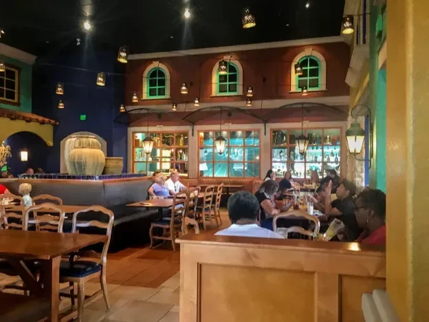 Busy restaurant interior with colorful decor, diners, and a prominent bar.
