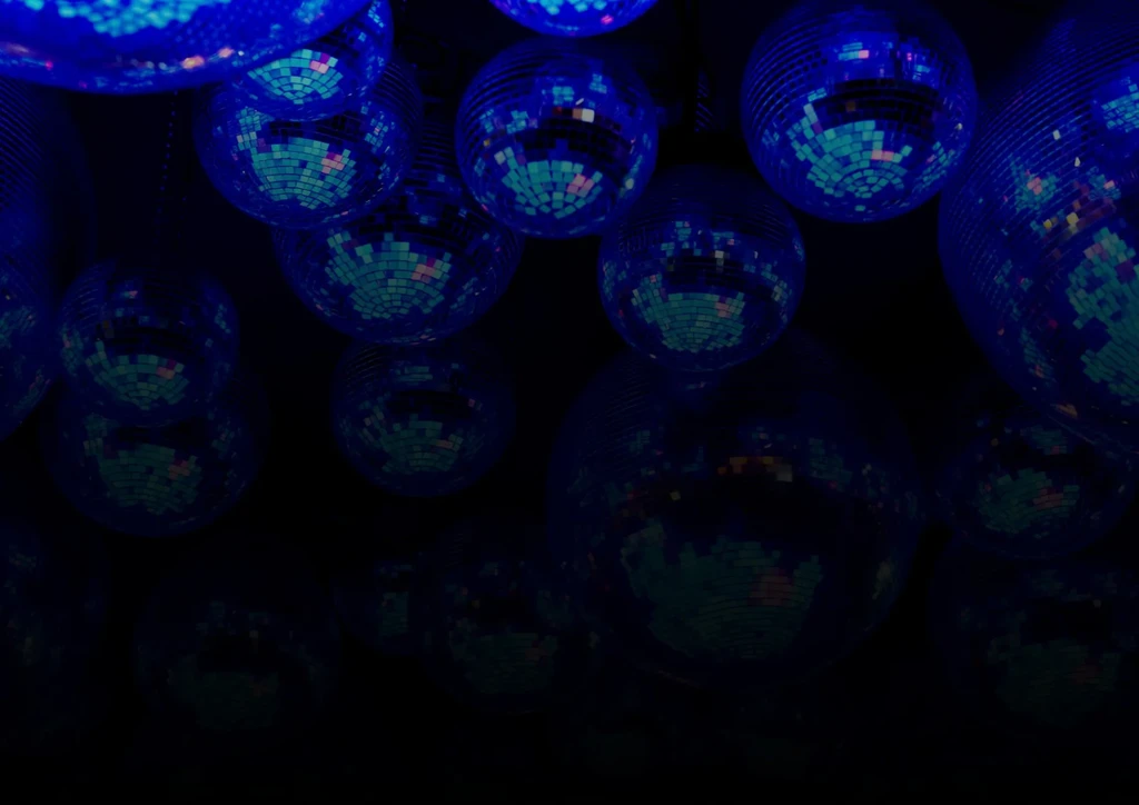 Multiple disco balls reflecting blue and teal light on black.