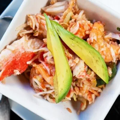 Close-up of shredded crab salad with avocado in a white bowl.