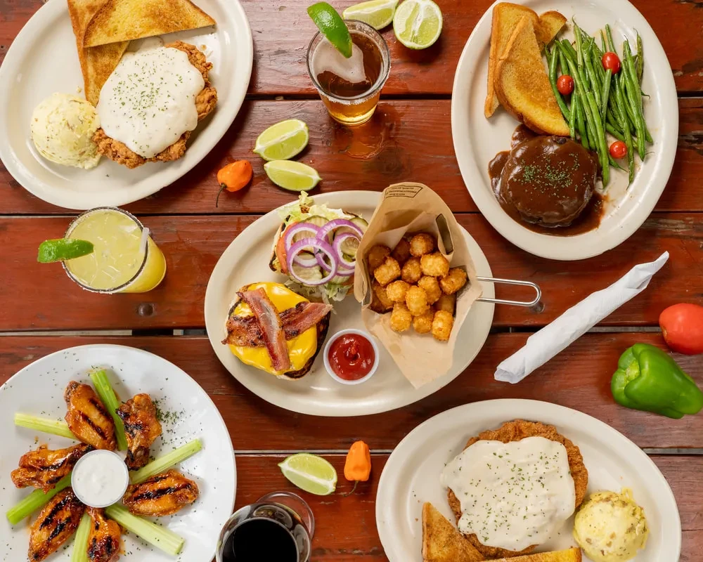 Overhead view of diverse American comfort food and drinks on rustic table.