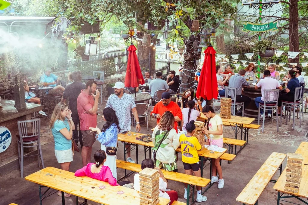 Bustling outdoor beer garden with patrons dining, drinking, and socializing.