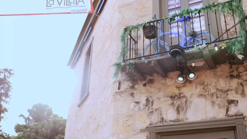 Old stone building with ornate balcony, blue bicycle, lights, and banner.
