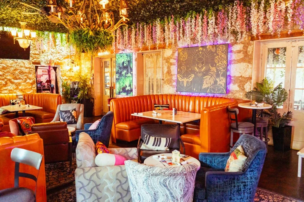 Whimsical restaurant with orange booth, floral ceiling, and mystical artwork.