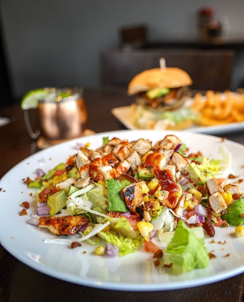 Colorful grilled chicken salad with avocado, corn, and bacon bits.